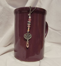 Load image into Gallery viewer, Artisan designed and handcrafted loose leaf tea ball infuser decorated with precious pink and white bead and a beautiful silver colour scroll heart charm, hanging from a mug. This tea infuser add bling to your tea cup or mug as your loose leaf tea steeps.
